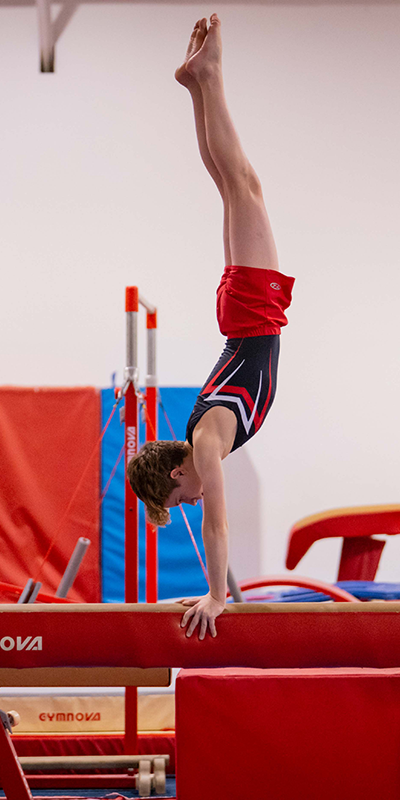 Gymnast doing handstand on beam